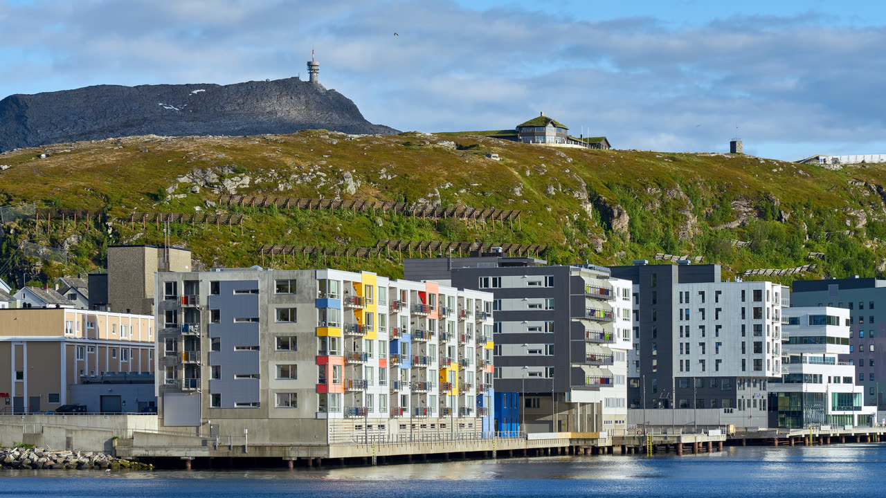 Hammerfest havn med fargerike boligbygg og fjellet Salen i bakgrunnen