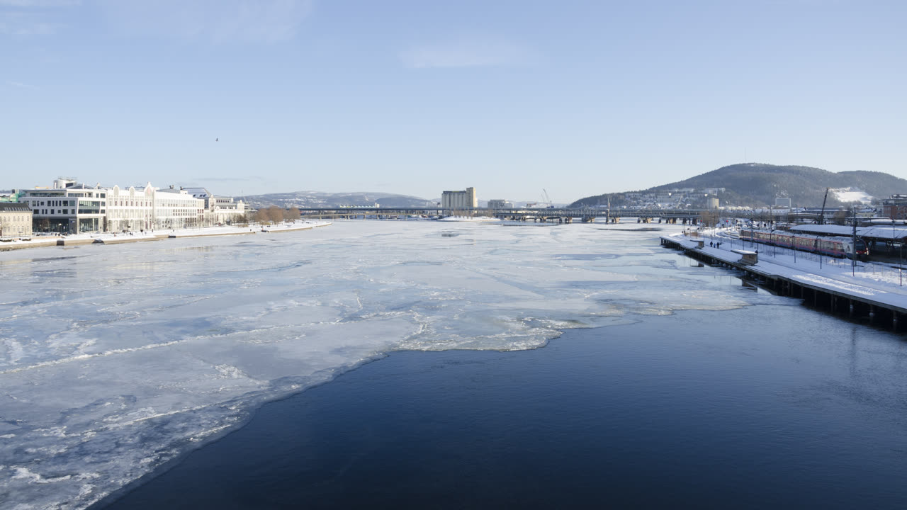 Drammen ved Drammenselva en vinterdag, med is på elva, snødekte bredder og bebyggelse i sentrum
