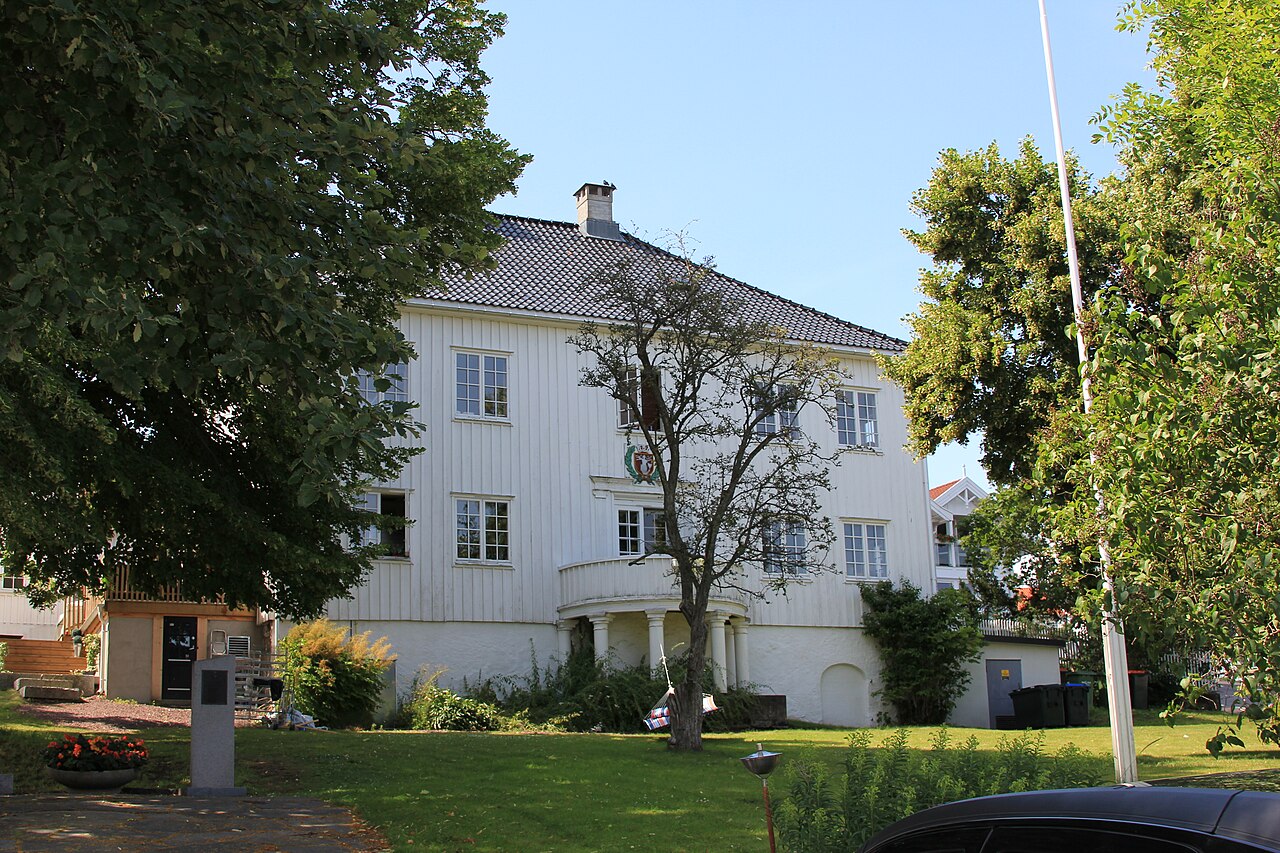 Hvite trehus langs en gate i Åsgårdstrand, med fjorden i bakgrunnen