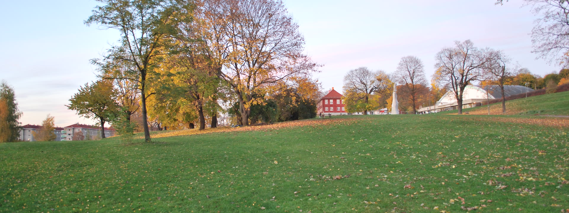 Tøyenparken i Oslo med grønne plener, trær og boligblokker i bakgrunnen