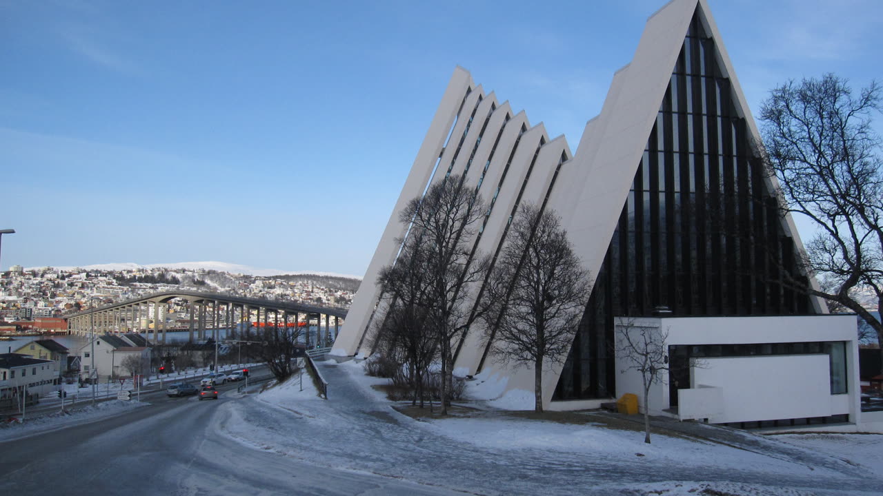 Ishavskatedralen og Tromsøbrua over Tromsøya med den snødekte byen og fjellene bak en vinterdag