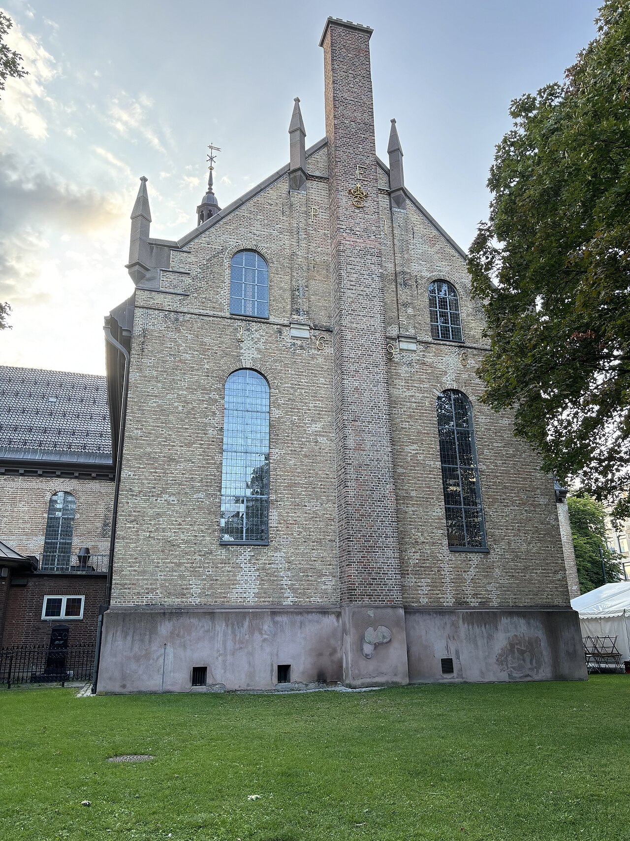 Oslo domkirke sett fra kirkehagen, med barokkfasaden og klokketårnet mot kveldshimmelen