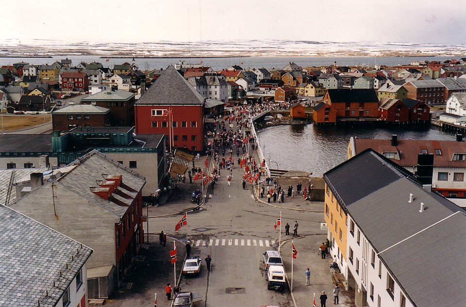 Folkeliv med norske flagg i Vardø sentrum ved havnen på en festdag