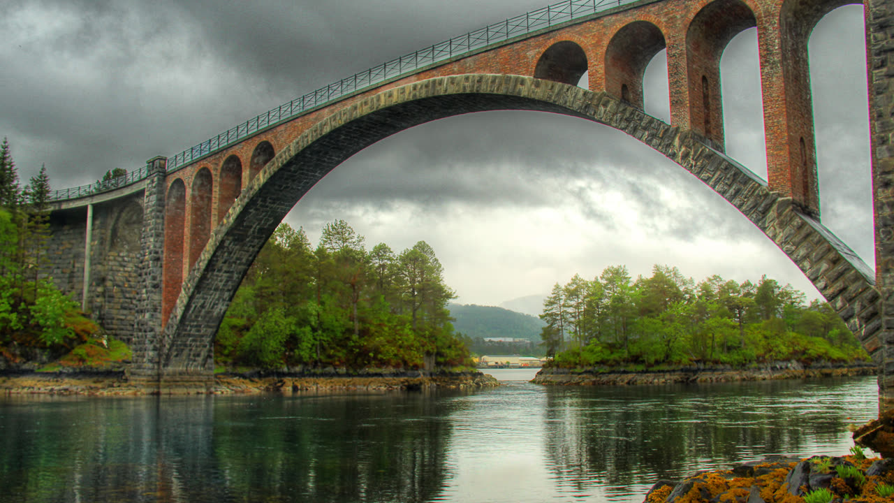 Skodjebruene, de historiske steinbruene over Straumen-sundet ved Skodje, med fjordvann og grønne holmer en sommerdag