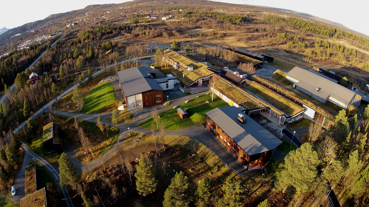 Flyfoto over Beitostølen i Øystre Slidre en snøfri sommerdag, med grønne jorder og fjellbjørkeskog