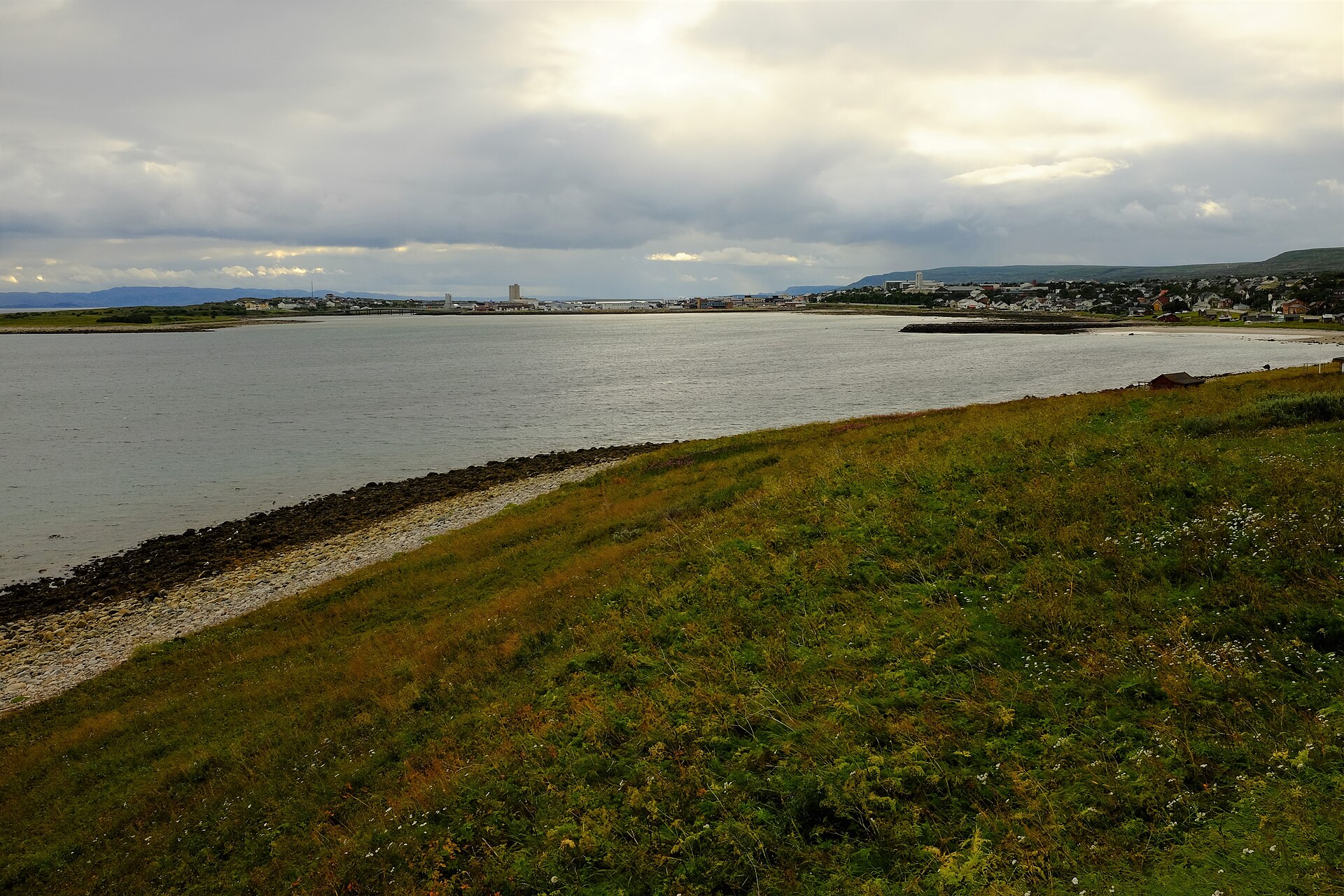 Vadsø by ved Varangerfjorden i Finnmark, sett fra Navarsodden, med lave bygg og fjell i bakgrunnen