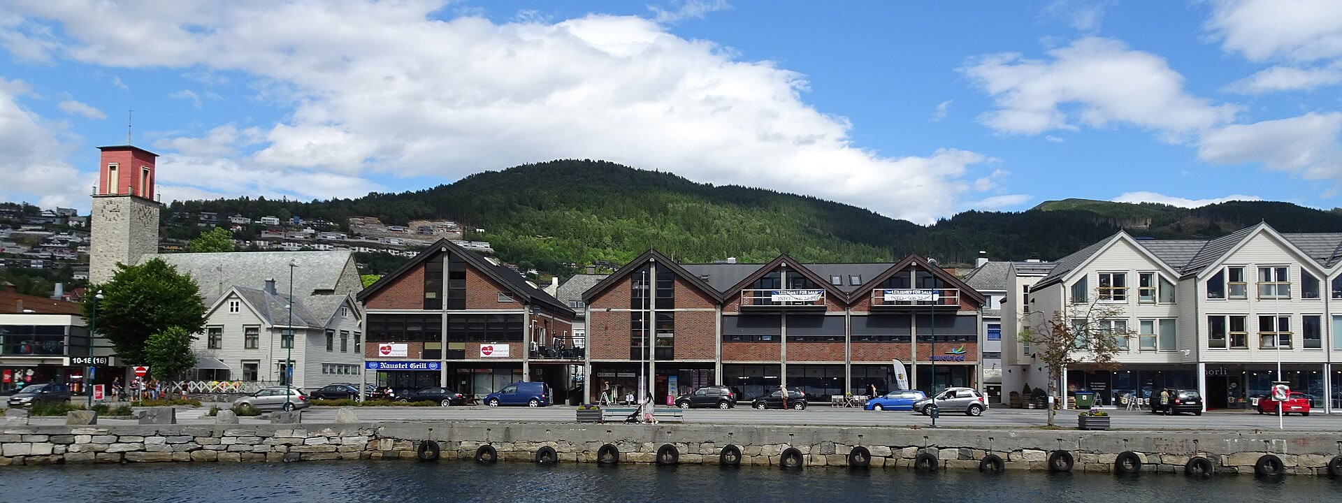 Volda sentrum med bryggekanten, sentrumsbygg og grønne fjell i bakgrunnen