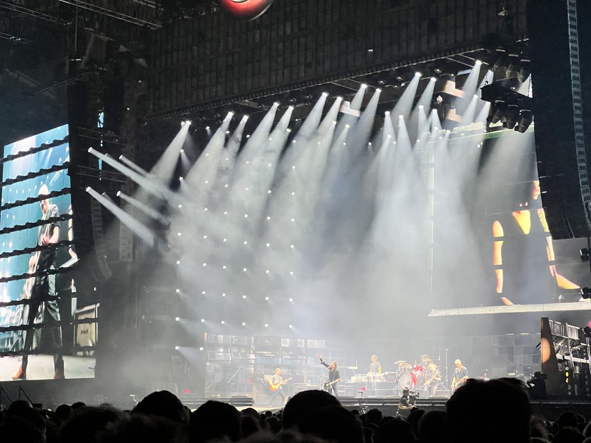 Foo Fighters på scenen i Unity Arena under hvite lyskjegler, publikum i silhuett foran scenen