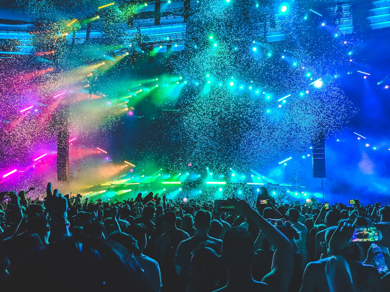 Konsertscene med laserlys og publikum i en stor arena