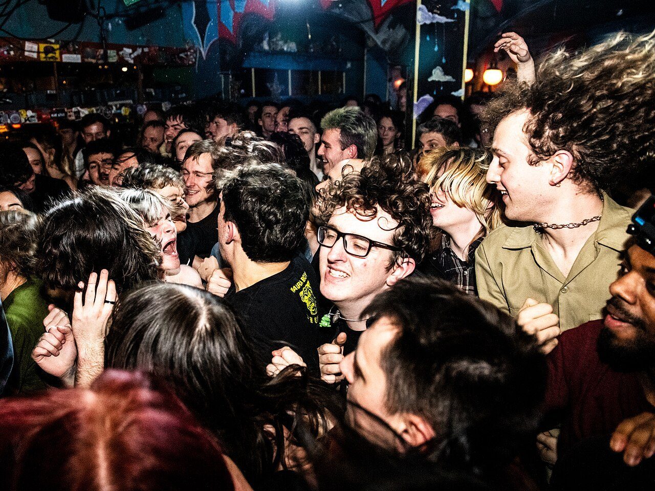 Konsertpublikum i mørkt lokale med scenebelysning